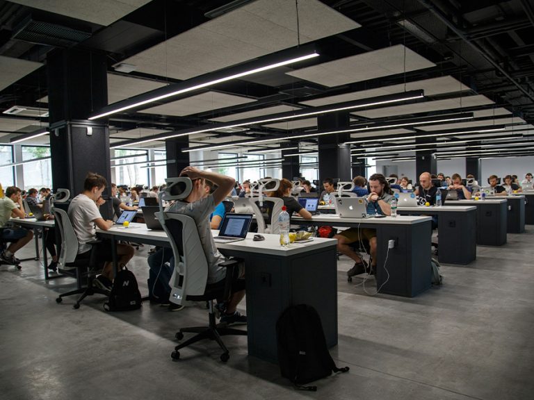 A busy and modern open plan office with people working at their desks. Image: Alex Kotliarskyi/Unsplash