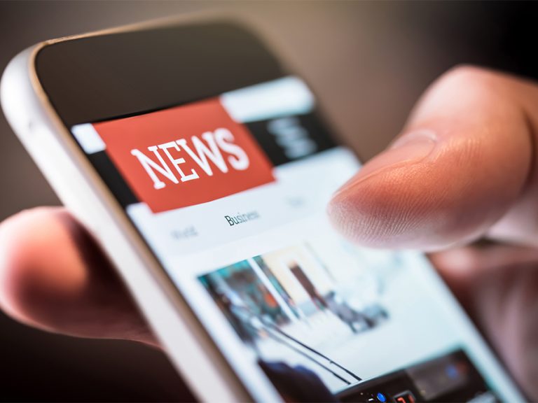 A news website on a mobile device being held by someone reading what is on the page. Image:Tero Vesalainen/Shutterstock