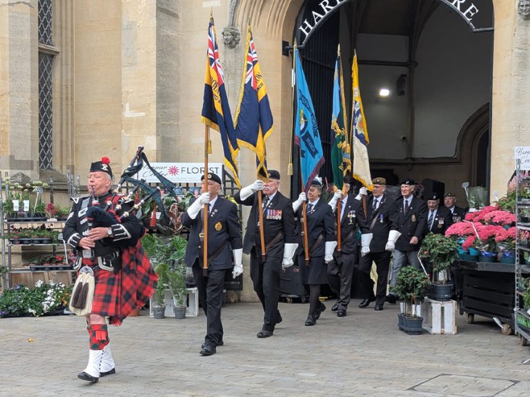 A piper from the Bedford Pipe Band leads RBL standard bearers and former service men and women onto Harpur Square ahead of the commemorative raising of a VE Day 80 flag. Image: Bedford Borough Council
