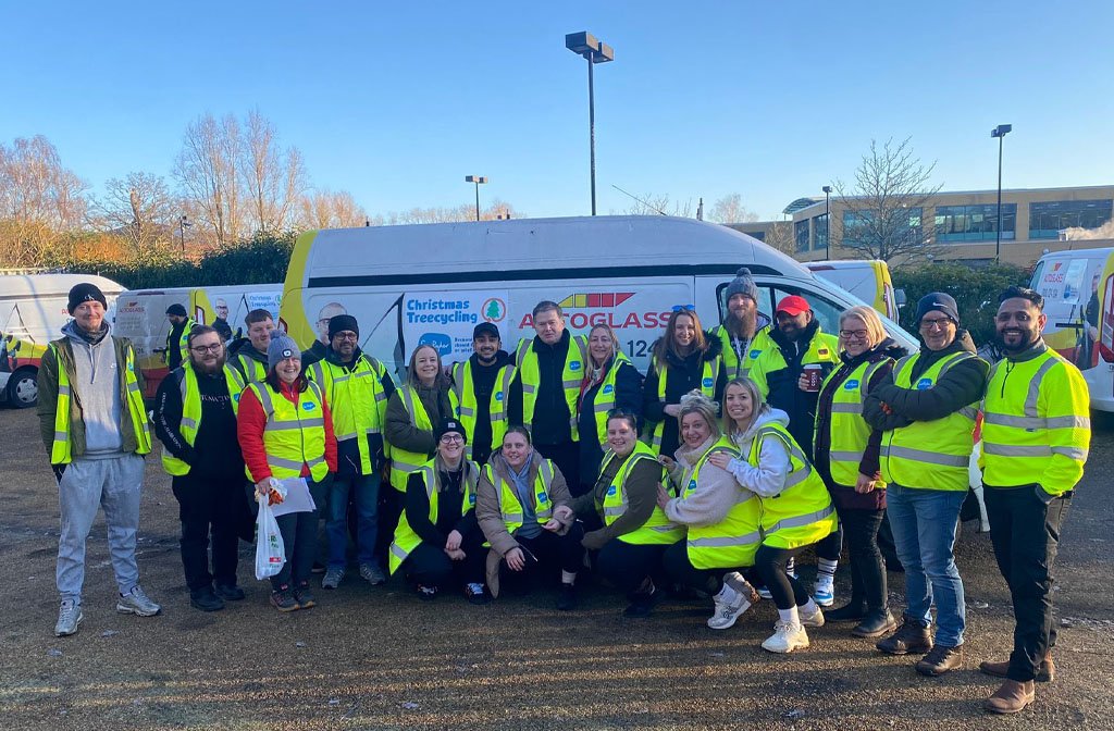 A team photo of volunteers from Autoglass in Bedford. They are dressed in hi-vis jackets and are in front of an Autoglass van.