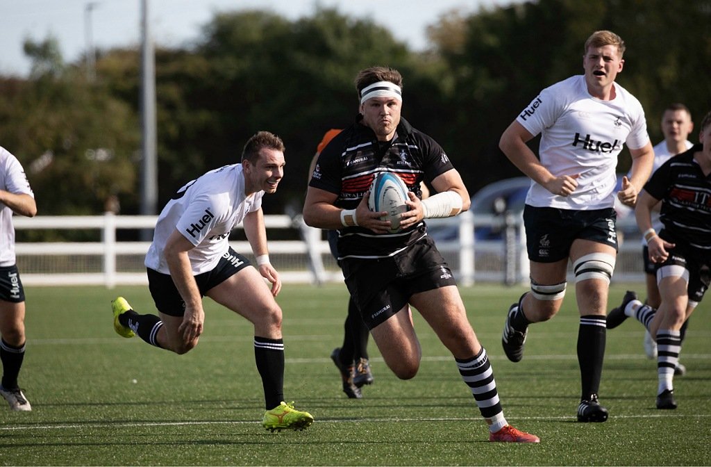 Bedford Ath player runs away from a Tring tackle on the rugby pitch