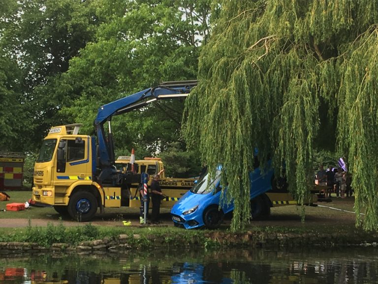 A blue car being lifted out of the River Great Ouse during the kite festival