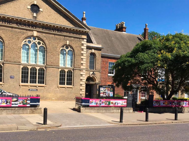 The Quarry Theatre is the location for much of the Bedfringe programme. It is pictured with lots of bright pink Bedringe posters on its railings.