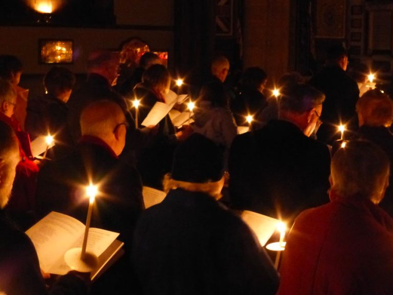 Christingle candles illuminating hymn books in a darkened church