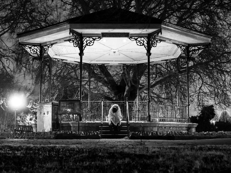 Homeless person sitting in Bedford Mill Meadows bandstand