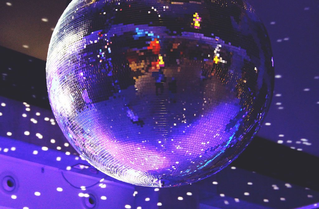 A close up image of disco glitter ball relecting on the surrounding room