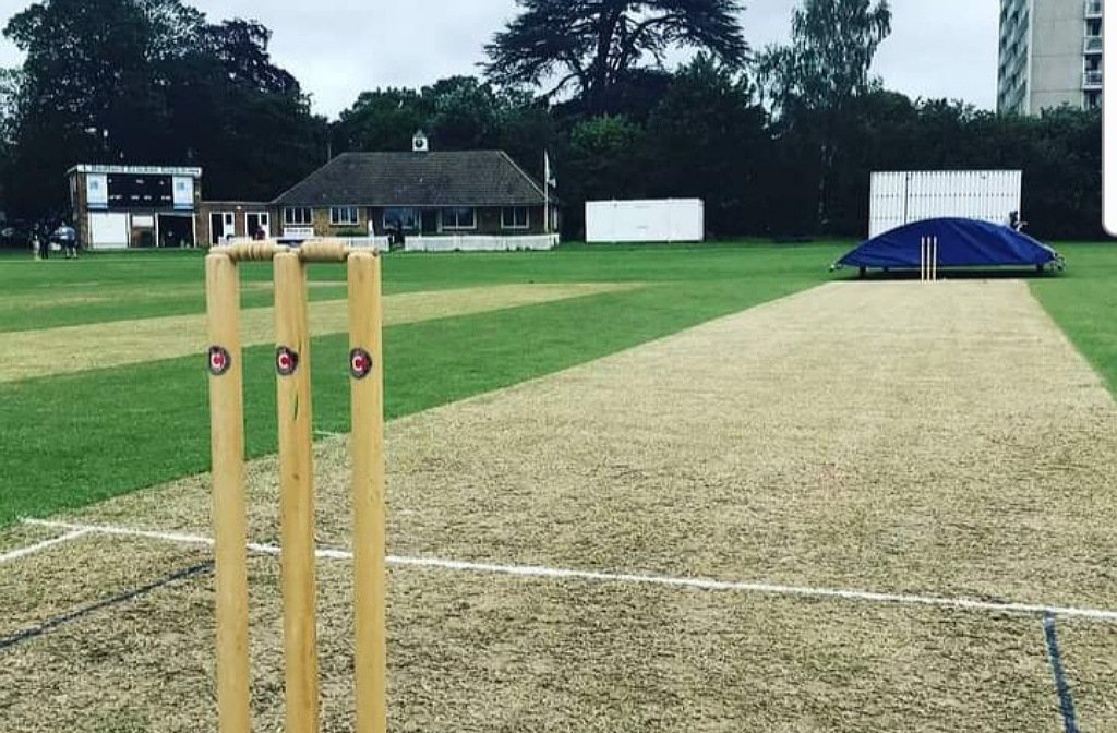 Image of cricket stumps in the foreground with Bedford Cricket Club pavilion in the background