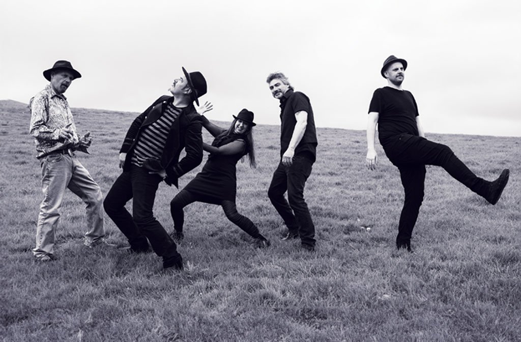 The five members of Mad Dog Mcrae and picutured in black and white 'frolicking' on a grassy hillside