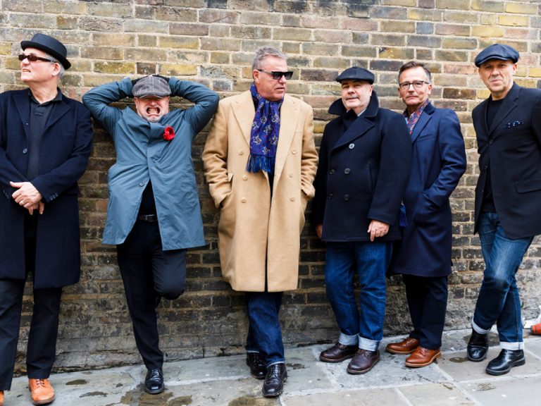 The Ska band Madness standing in front of a brick wall