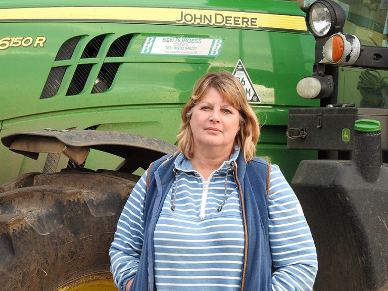 NFU Bedfordshire and Huntingdonshire chair Freya Morgan standing in front of a large, green John Deere tractor. Image NFU