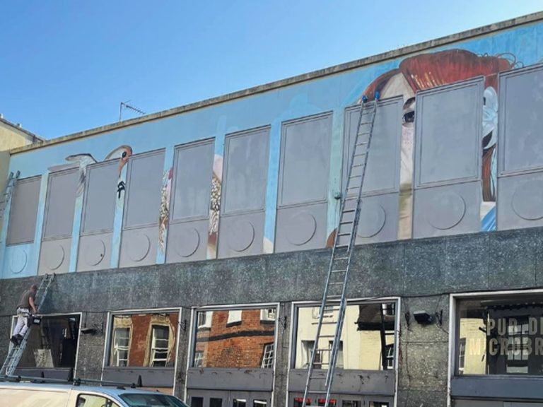 Painters painting over the mural of Ninkasi on Bedford High Street. Image @kaczorowskicallum/@SimplyBedford/Instagram