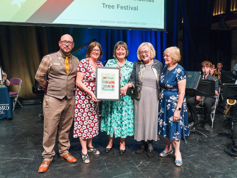 Progress Publishing's Paul Hutchinson, standing in for White Hart Press, presents the award for Fundraiser of the Year (Team) 2024 to the Bedford Christmas Tree Festival committee. Image: Bedford Independent