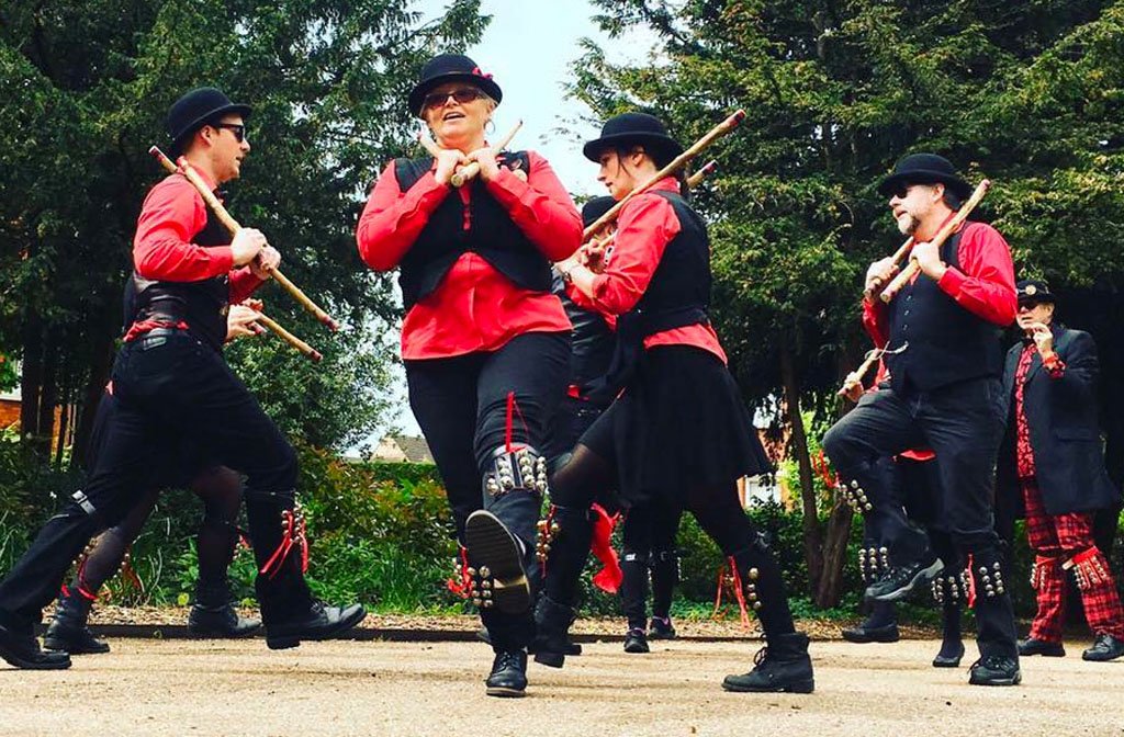 Members of Red Cuthbert Morris Dancers performing in their red shirts, black waistcoats, hats and trousers