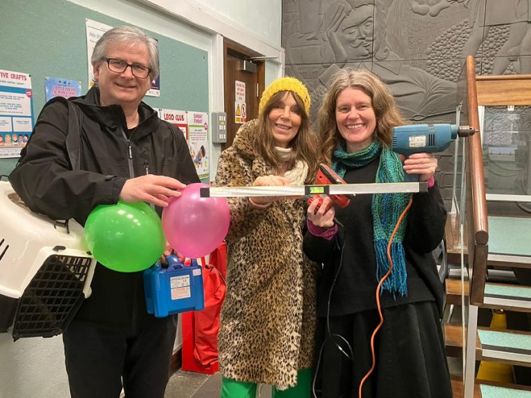 Share Bedford volunteers (Richard Baker, Gabby Smith and Susan Throssell in the foyer of Bedford Central Library with a cat carrier, balloons, a spirit level and an electric drill to launch the library of things. Image: Share Bedford