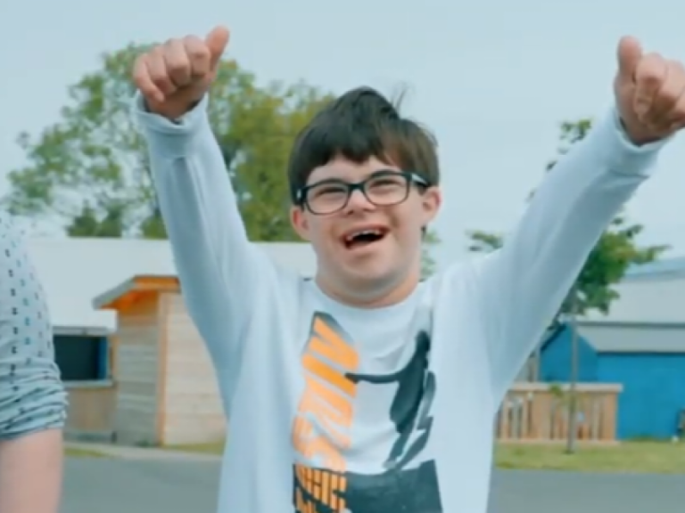 SEND child with their arms in the air and with their thumbs up.