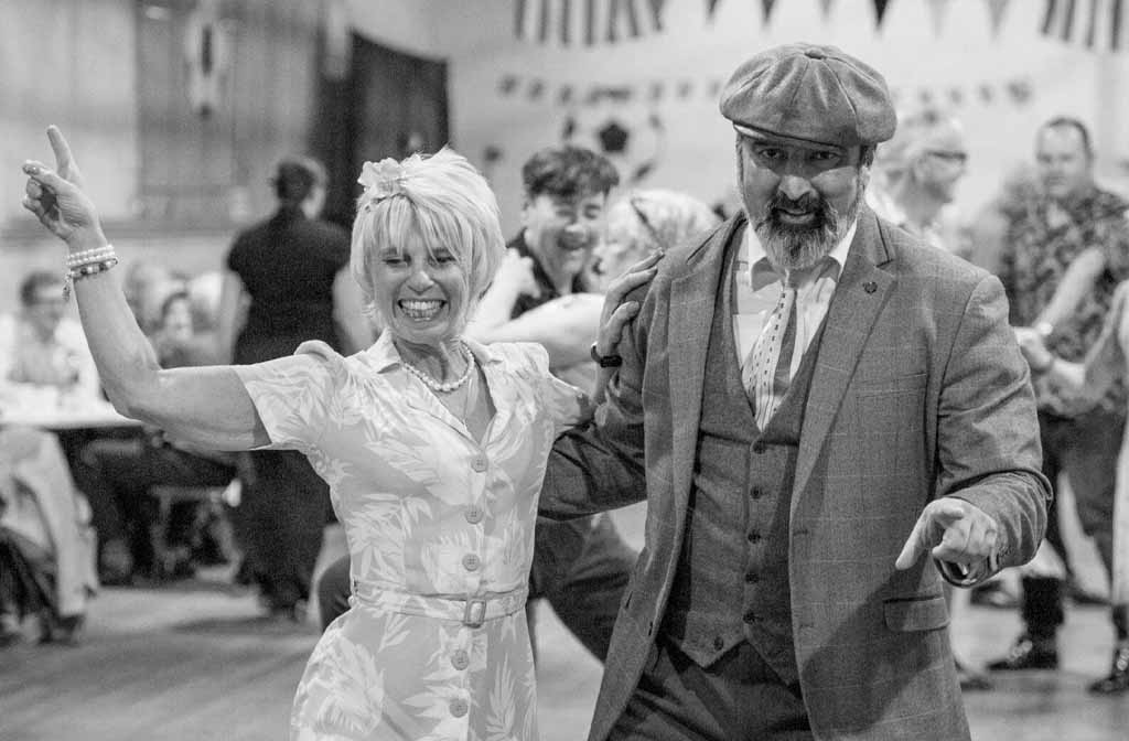 A man and a woman, dressed in vintage clothing, are dancing.
