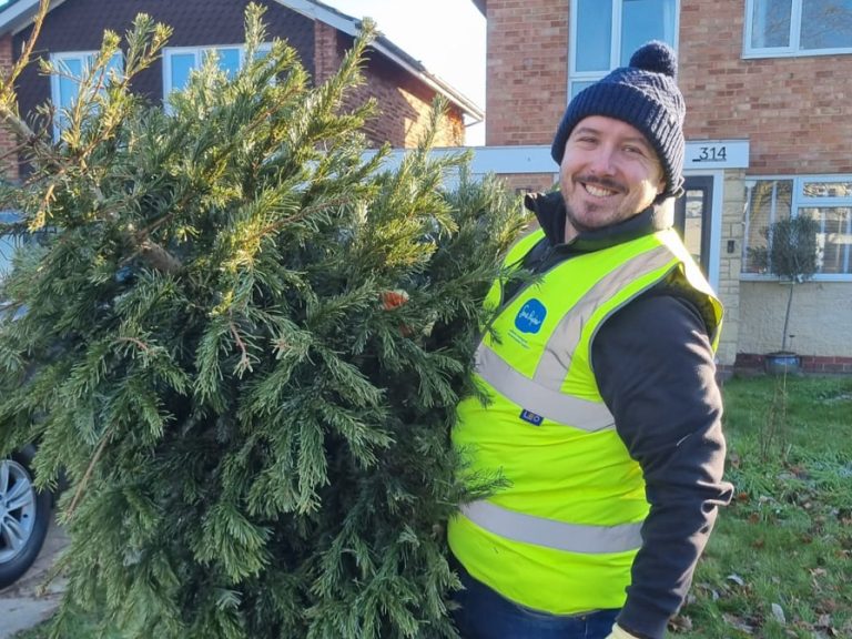A volunteer from Sue Ryder carrying a Christmas tree as part of the Treecycling initiative. Image: Sue Ryder