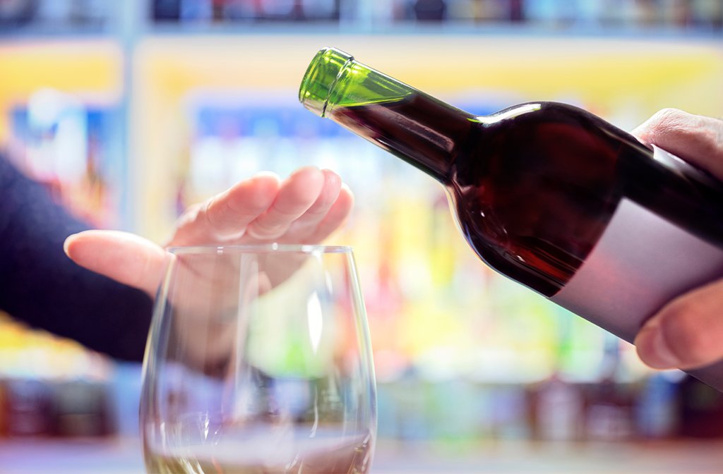Woman hand rejecting more alcohol from wine bottle in bar Image Brian Jackson Adobe Stock
