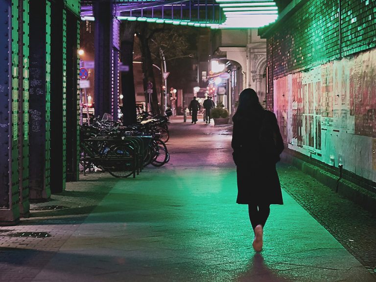 Woman walking alone at night under a bridge Image: Norbert Braun/Unsplash