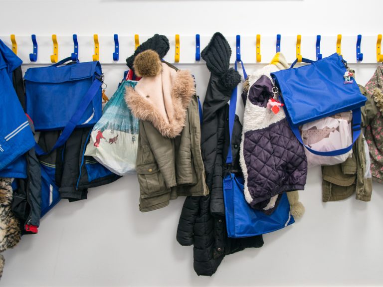 A row of children's coats on a coat wrack at a primary school