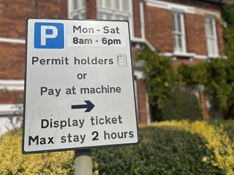 a parking permit sign on a Bedford street displaying the times tickets are required
