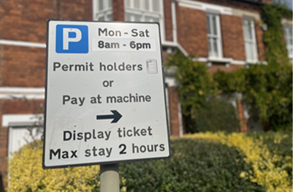 a parking permit sign on a Bedford street displaying the times tickets are required