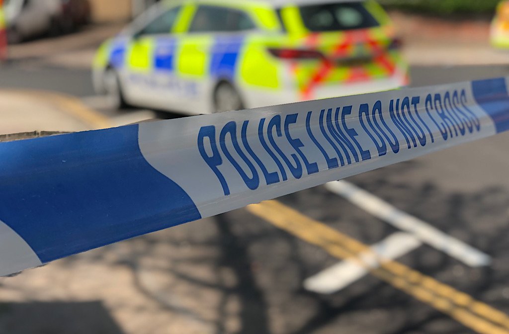 A generic picture of 'police line do not cross tape' with a police car in the background