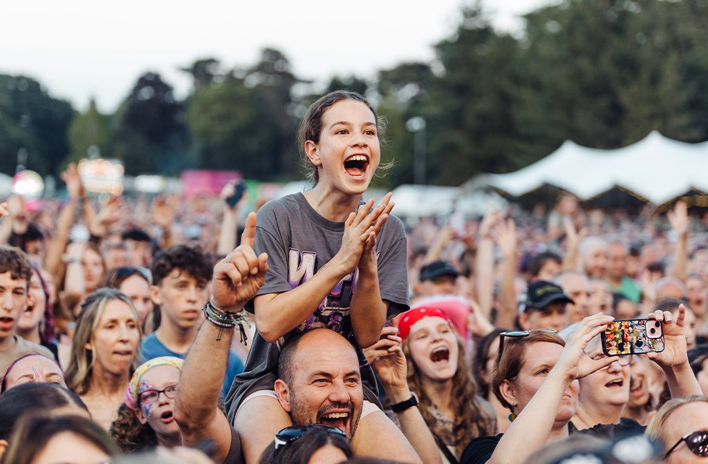 A McFly fan on her dad's shoulders, beams from ear to ear as the band take to the stage. Image: Cuffe & Taylor