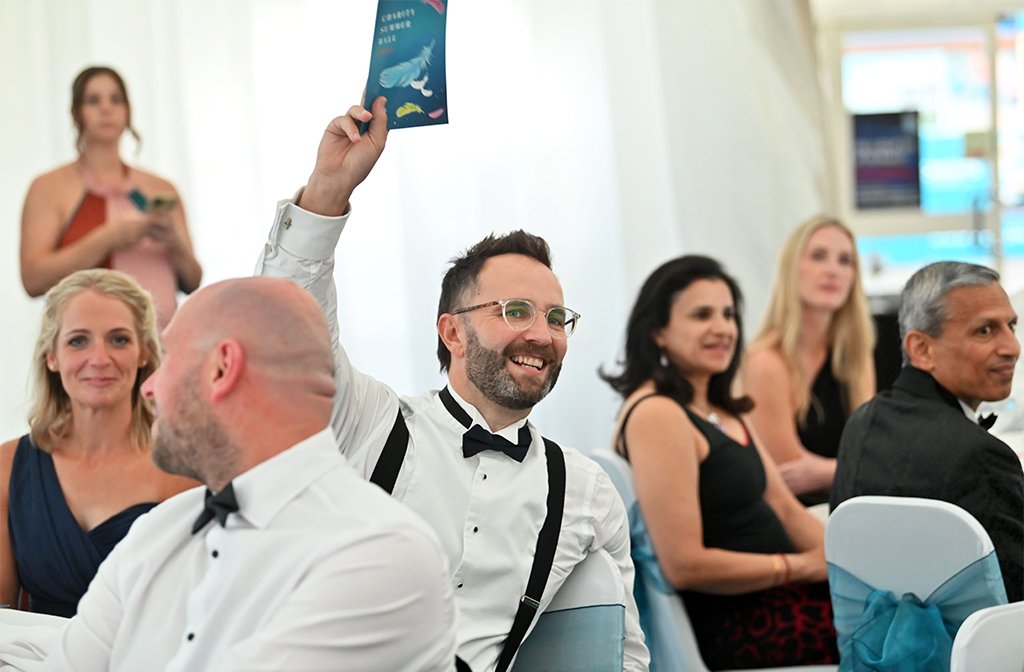 A man in a white shirt and black tie makes a bid during the auction at the Towers Summer Ball 2025. Image: Club Towers