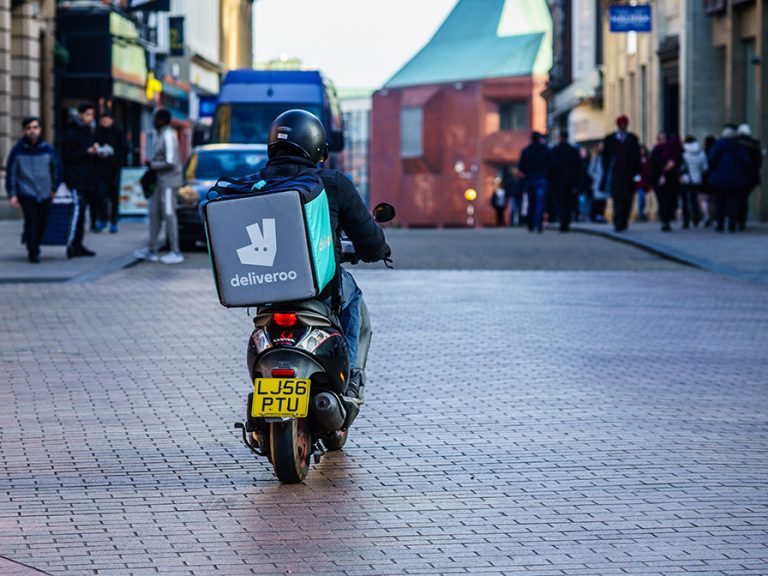 Delivery driver on their motorbike in a UK street image nrqemi:Shutterstock
