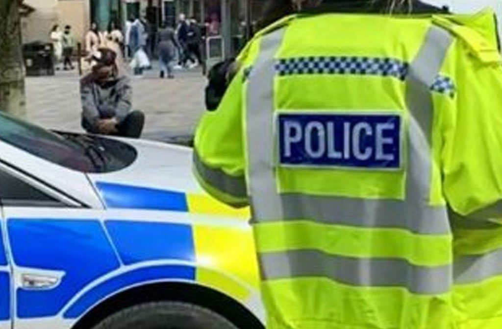 A police officer is photographed from the rear wearing a high viz jacket with POLICE on the back