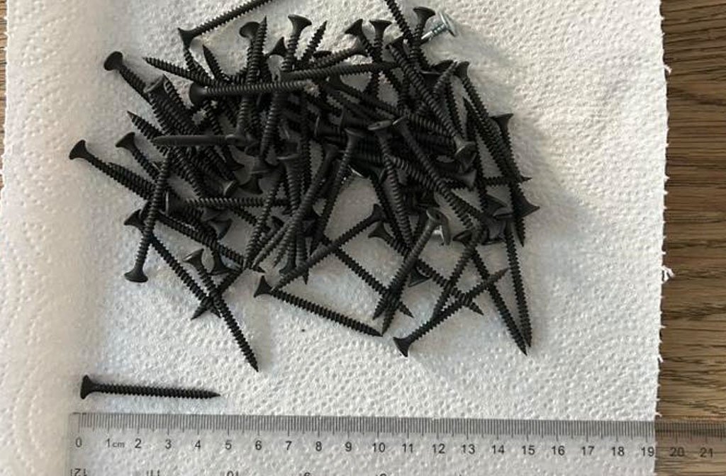 Discarded screws alongside a ruler to demonstrate their size