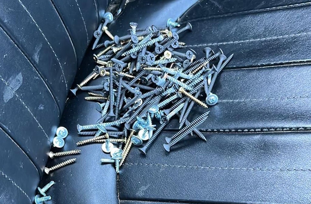 Discarded screws collected on a car seat.