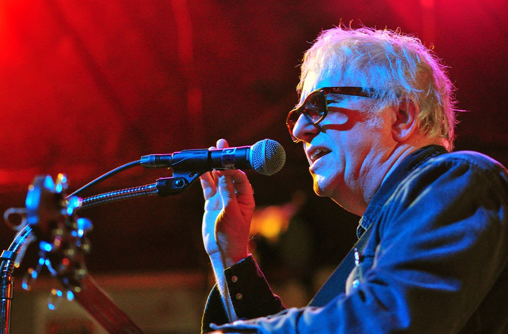 Wreckless Eric holding a guitar and singing into a microphone
