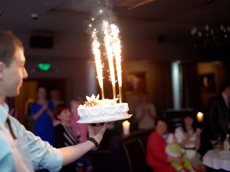 A waiter bringing out a cake with fountain sparklers at a restaurant Image Olexandr Panchenko Shutterstock