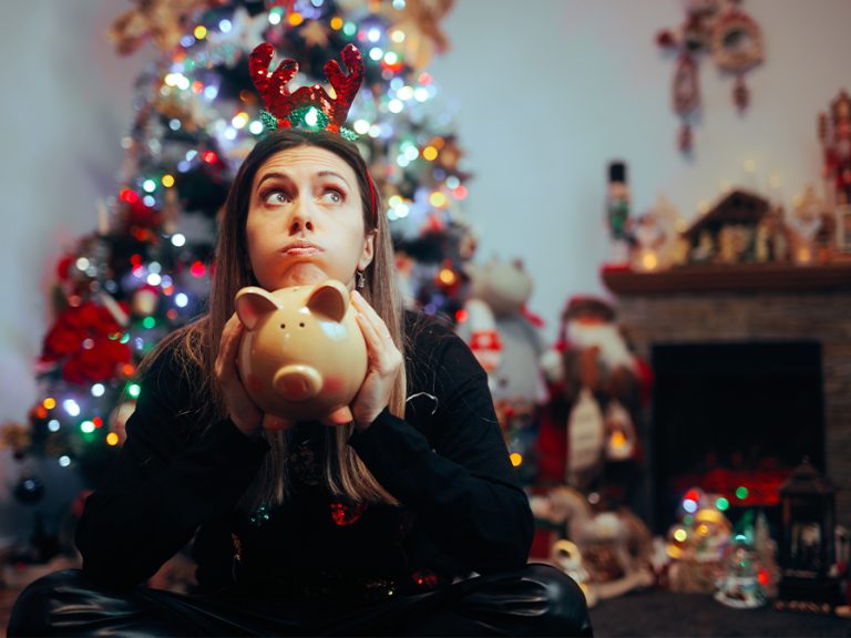 Broke Woman Holding a Piggy Bank in a Christmas setting.Budget Money Cash Image Nicoleta Ionescu Shutterstock