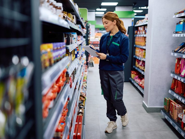 Female worker taking notes while checking stock of shelves at supermarket. Image Drazen Zigic Shutterstock