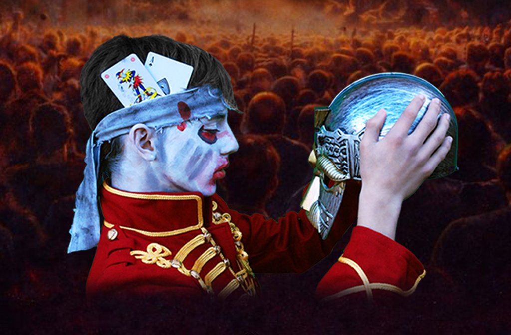 A young man in regimental dress and a headband holding two playing cards is holding up a metal helmet