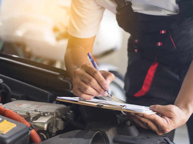 Mechanic checking a car van engine MOT garage workshop Image Pormezz Shutterstock