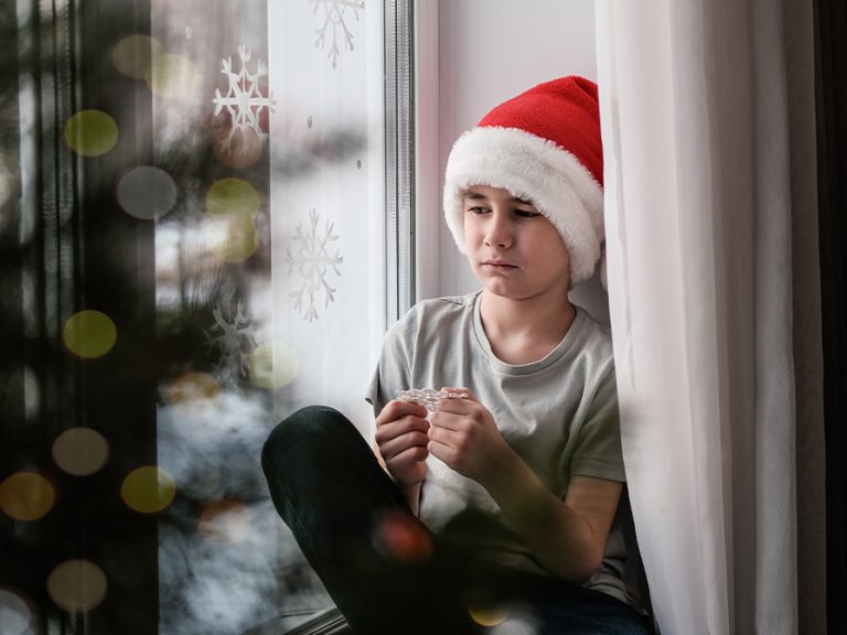 Sad boy in Christmas hat sits by the window. Image: Elen Nika/Shutterstock