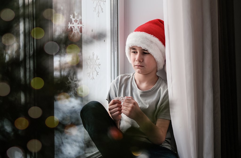 Sad boy in Christmas hat sits by the window. Image: Elen Nika/Shutterstock