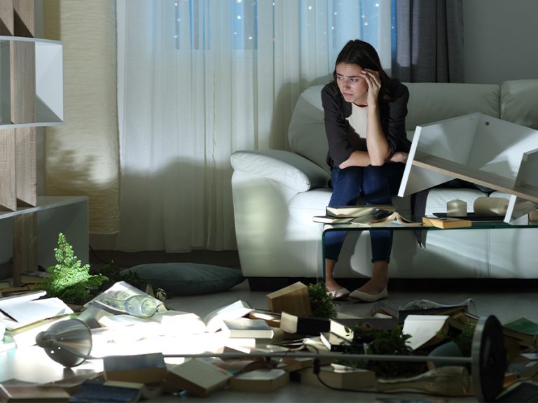 Sad woman alone in the night after robbery sitting on a couch at home Image Pheelings media Shutterstock