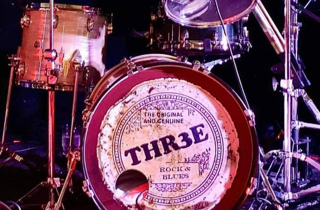 A drum kit with the band name Thr3e