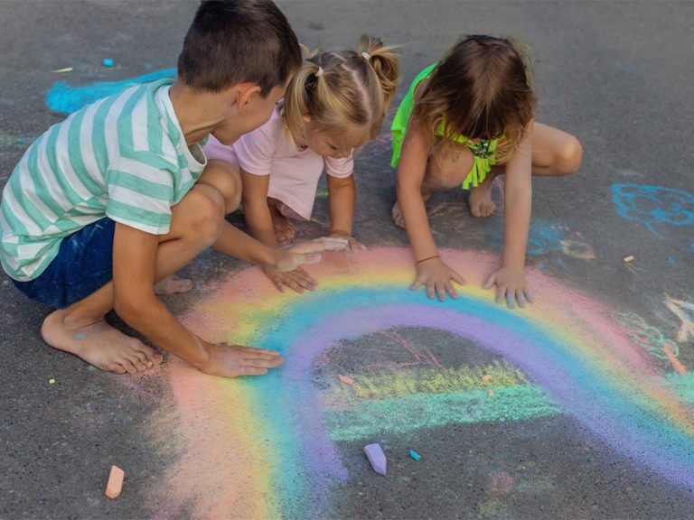 Children draw a colourful picture with chalk on the playground tarmac Image Anuta23 Shutterstock