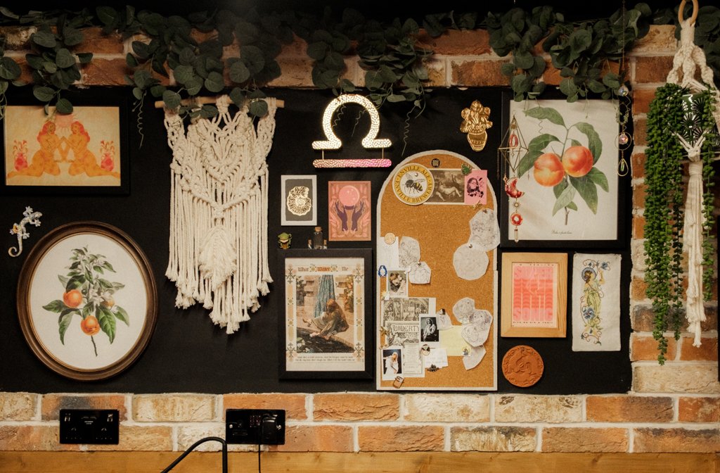 A wall of inspiration including postcards, macrame, flyers and paintings at Evermore Tattoo Parlour
