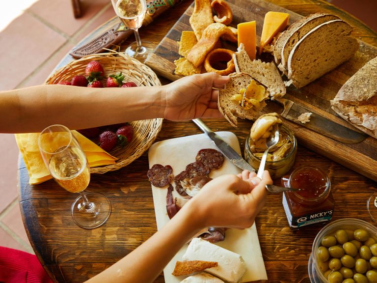 A person holding a bread and a spoon with dip near the table with food and champagne Image Laker Pexels