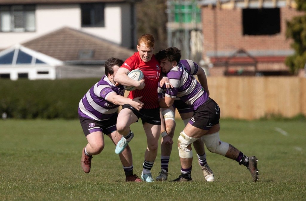 A Bedford Athletic rugby player holds three Stamford defenders at bay