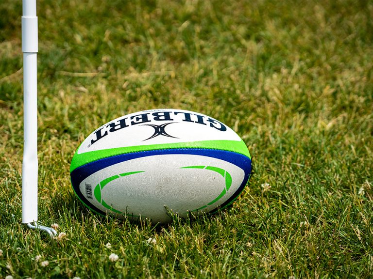 a rugby ball sitting on top of a lush green field Image Chris Robert Unsplash