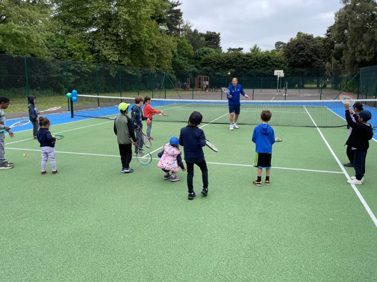 Stock image of a tennis coach guiding youngsters on a Bedford Borough Council owned tennis court