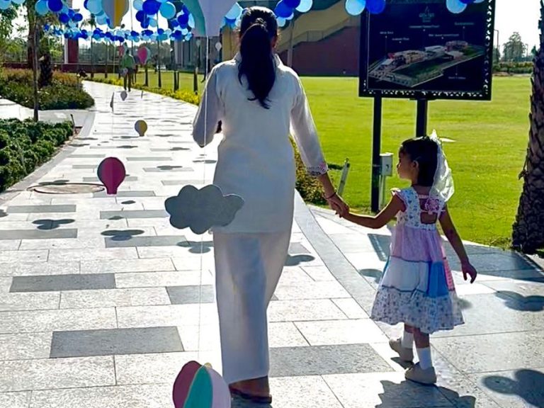 A mother and daughter are walking down a path decorated by balloons